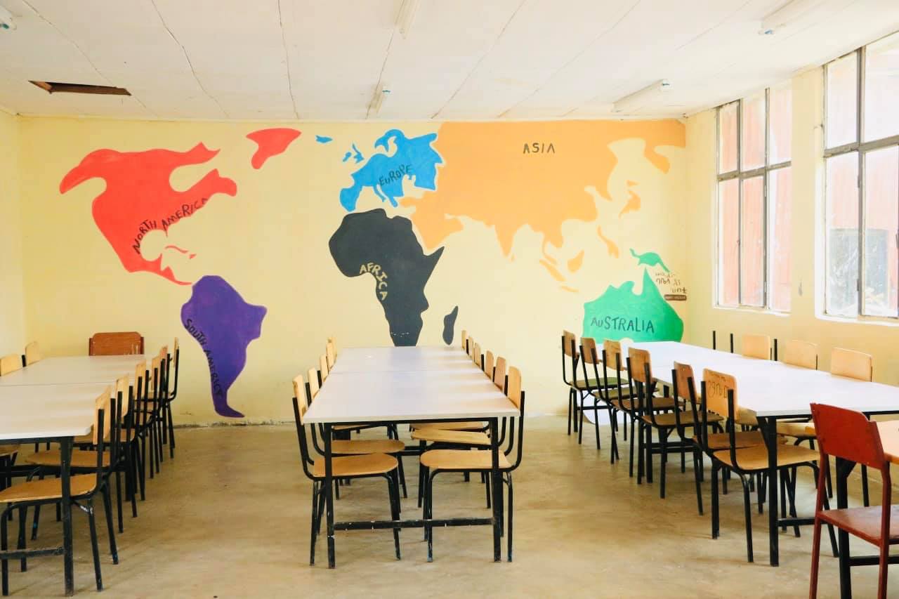 Reading tables under a painted world map in the Burka Wayo library